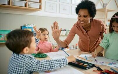 zdjęcie przedstawia dzieci i dosrosłą kobietę przybijających piątkę